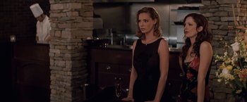 Movie still from “27 Dresses” (2008), directed by Anne Fletcher – A woman standing in front of a glass of wine; Medium shot, Over the shoulder angle