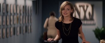 Movie still from “27 Dresses” (2008), directed by Anne Fletcher – A woman in a black shirt holding a black purse; Medium shot, Over the shoulder angle