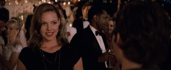 Movie still from “27 Dresses” (2008), directed by Anne Fletcher – A group of people at a formal event; Close Up shot, Over the shoulder angle