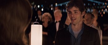Movie still from “27 Dresses” (2008), directed by Anne Fletcher – A young man standing in front of a group of people; Close Up shot, Over the shoulder angle