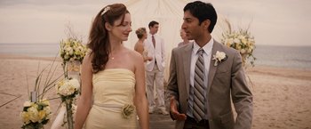 Movie still from “27 Dresses” (2008), directed by Anne Fletcher – A man and a woman standing next to each other in front of other people; Medium shot, Over the shoulder angle