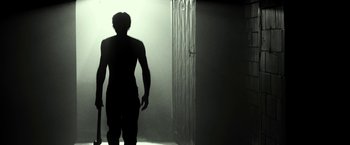 Movie still from “31” (2016), directed by Rob Zombie – A man standing in front of an open shower door; Wide shot, Low angle