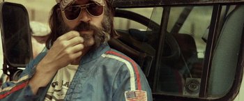 Movie still from “31” (2016), directed by Rob Zombie – A man with a beard and sunglasses in a car; Close Up shot, Low angle
