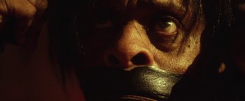 Movie still from “31” (2016), directed by Rob Zombie – A man with a mouth taped shut with his eyes wide open; Extreme Close Up shot, High angle