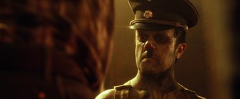 Movie still from “31” (2016), directed by Rob Zombie – A man in a military uniform looking into a mirror; Close Up shot, Over the shoulder angle
