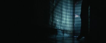 Movie still from “31” (2016), directed by Rob Zombie – A dark room with a light shining on the wall; Wide shot, Low angle