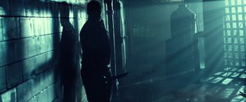 Movie still from “31” (2016), directed by Rob Zombie – A person holding a knife in a dark room; Wide shot, Low angle