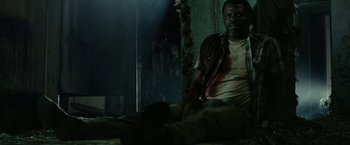 Movie still from “31” (2016), directed by Rob Zombie – A man sitting on the ground in a dark room; Medium shot, Low angle