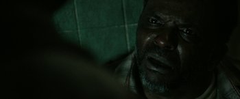 Movie still from “31” (2016), directed by Rob Zombie – A man's face in a dark room; Extreme Close Up shot, Over the shoulder angle