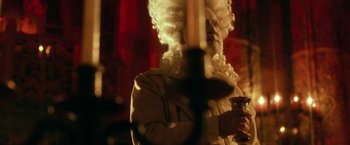 Movie still from “31” (2016), directed by Rob Zombie – A man in a white wig holding a glass; Close Up shot, Over the shoulder angle