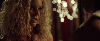 Movie still from “31” (2016), directed by Rob Zombie – A woman with long blonde curly hair stares at the camera; Close Up shot, Over the shoulder angle
