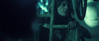 Movie still from “31” (2016), directed by Rob Zombie – An old woman looking through a window at night; Close Up shot, Over the shoulder angle