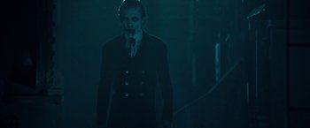 Movie still from “31” (2016), directed by Rob Zombie – A man in a suit and mask standing in the dark; Medium shot, Over the shoulder angle