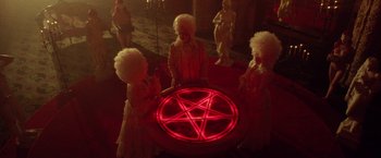 Movie still from “31” (2016), directed by Rob Zombie – A group of people dressed as witches around a table with a pentagram on it; Wide shot, High angle