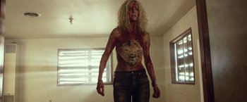 Movie still from “31” (2016), directed by Rob Zombie – A woman with blonde curly hair and some blood all over her body; Medium shot, Overhead angle