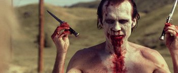 Movie still from “31” (2016), directed by Rob Zombie – A man with blood all over his face holding a gun; Close Up shot, Over the shoulder angle