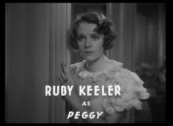 Movie still from “42nd Street” (1933), directed by Lloyd Bacon – A black - and - white photo of a woman in a white dress; Close Up shot, Low angle