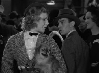 Movie still from “42nd Street” (1933), directed by Lloyd Bacon – A man and a woman holding a dog; Medium shot, Low angle