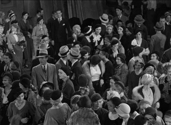 Movie still from “42nd Street” (1933), directed by Lloyd Bacon – A group of people wearing hats in a room; Wide shot, High angle