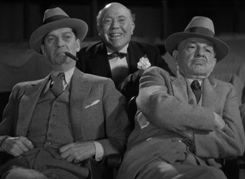 Movie still from “42nd Street” (1933), directed by Lloyd Bacon – A group of men sitting next to each other wearing hats; Medium shot, Low angle