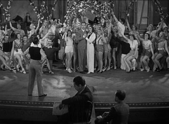Movie still from “42nd Street” (1933), directed by Lloyd Bacon – A black and white photo of a group of people on a stage; Wide shot, High angle