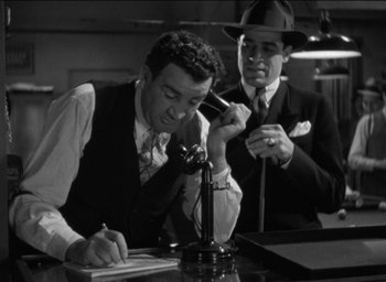 Movie still from “42nd Street” (1933), directed by Lloyd Bacon – Two men sitting at a table with a phone; Medium shot, Low angle