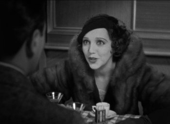 Movie still from “42nd Street” (1933), directed by Lloyd Bacon – An old photo of a woman sitting at a dinner table; Close Up shot, Over the shoulder angle