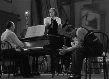 Movie still from “42nd Street” (1933), directed by Lloyd Bacon – A man and a woman are playing piano in a room; Wide shot, High angle