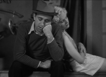 Movie still from “42nd Street” (1933), directed by Lloyd Bacon – A man and a woman sitting next to each other on the ground; Medium shot, High angle