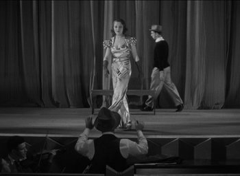 Movie still from “42nd Street” (1933), directed by Lloyd Bacon – A woman standing on a stage in front of two men; Wide shot, High angle
