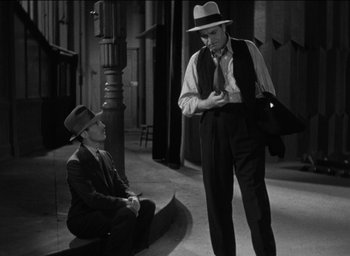 Movie still from “42nd Street” (1933), directed by Lloyd Bacon – A man in a hat and a man in a suit; Medium shot, Over the shoulder angle