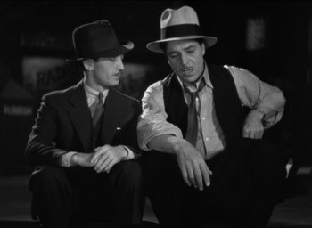 Movie still from “42nd Street” (1933), directed by Lloyd Bacon – A couple of men sitting next to each other on the ground; Medium shot, Low angle