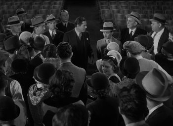 Movie still from “42nd Street” (1933), directed by Lloyd Bacon – A group of men and women wearing hats and suits; Wide shot, High angle