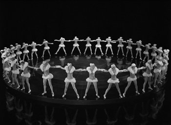 Movie still from “42nd Street” (1933), directed by Lloyd Bacon – A group of women are dancing in a circle on a stage; Extreme Wide shot, High angle