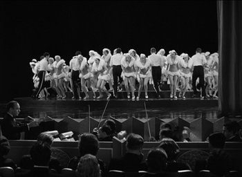 Movie still from “42nd Street” (1933), directed by Lloyd Bacon – A black and white photo of a group of people on a stage; Extreme Wide shot, High angle