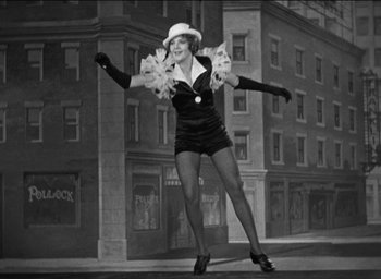Movie still from “42nd Street” (1933), directed by Lloyd Bacon – A black and white photo of a woman in a short dress and a hat; Wide shot, Low angle