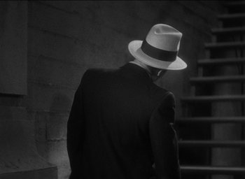 Movie still from “42nd Street” (1933), directed by Lloyd Bacon – A black and white photo of a man in a suit and a hat; Medium shot, Low angle