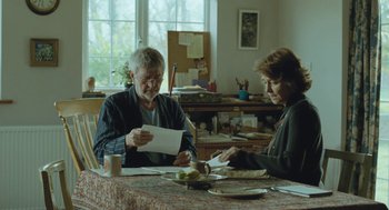 Movie still from “45 Years” (2015), directed by Andrew Haigh – A man and a woman sitting at a dining room table; Medium shot, Over the shoulder angle