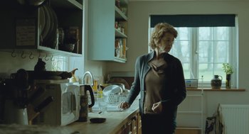 Movie still from “45 Years” (2015), directed by Andrew Haigh – A woman standing in a kitchen next to a microwave oven; Medium shot, Low angle