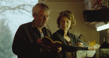 Movie still from “45 Years” (2015), directed by Andrew Haigh – A man and a woman are looking at a book; Medium shot, Low angle