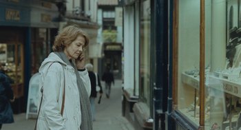 Movie still from “45 Years” (2015), directed by Andrew Haigh – A woman walking down a street talking on a cell phone; Medium shot, Over the shoulder angle