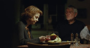 An older woman sitting at a table with a bowl of fruit