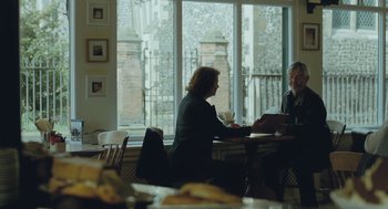 Movie still from “45 Years” (2015), directed by Andrew Haigh – Two people sitting at a table in front of a large window; Medium shot, Over the shoulder angle