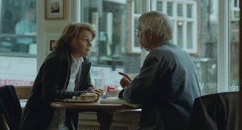 Movie still from “45 Years” (2015), directed by Andrew Haigh – An older man and a woman sitting at a table in front of each other; Medium shot, Over the shoulder angle