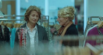 Movie still from “45 Years” (2015), directed by Andrew Haigh – Two women standing in a store talking to each other; Medium shot, Over the shoulder angle
