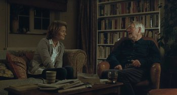 Movie still from “45 Years” (2015), directed by Andrew Haigh – A man and a woman sitting on a couch in a living room; Medium shot, Over the shoulder angle