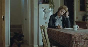 Movie still from “45 Years” (2015), directed by Andrew Haigh – A woman sitting at a table writing on a piece of paper; Medium shot, Over the shoulder angle