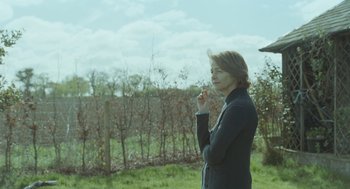 Movie still from “45 Years” (2015), directed by Andrew Haigh – A woman standing in front of a fence and trees; Medium shot, Over the shoulder angle