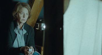 Movie still from “45 Years” (2015), directed by Andrew Haigh – A woman sitting in a chair holding a wii controller; Medium shot, Over the shoulder angle