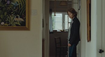 Movie still from “45 Years” (2015), directed by Andrew Haigh – A person standing in a room with a window in the background; Medium shot, Over the shoulder angle